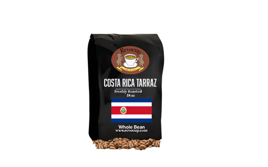 A black bag of Revocup Costa Rica Tarrazu Whole Bean coffee, 24 oz, stands upright on a pile of roasted coffee beans.